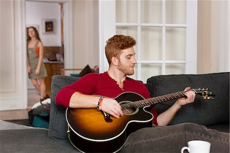 simsearch:693-03302055,k - Young man sitting sofa playing guitar Photographie de stock - Premium Libres de Droits, Code: 614-08392605