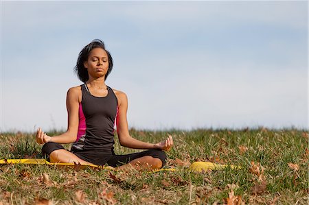 Young woman sitting on yoga mat, outdoors, in lotus position Stock Photo - Premium Royalty-Free, Code: 614-08392643