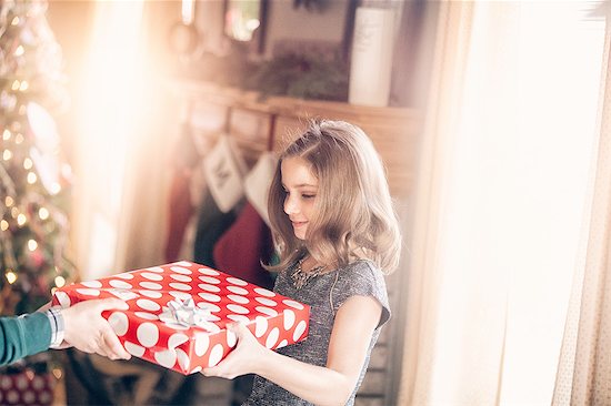 Side view of girl receiving gift at christmas looking down smiling Stock Photo - Premium Royalty-Free, Image code: 614-08392724