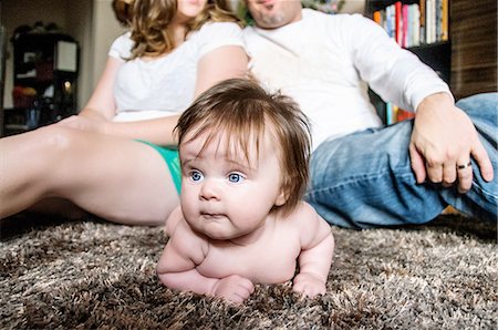 simsearch:614-06897884,k - Mother and father sitting back to back on rug with baby girl lying on rug looking away Foto de stock - Sin royalties Premium, Código: 614-08392729