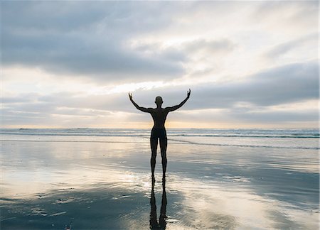 Silhouette of person raising arms on beach Stock Photo - Premium Royalty-Free, Code: 614-08487745