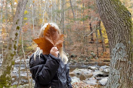 embarrassing fall - Girl covering face with maple leaf in forest Stock Photo - Premium Royalty-Free, Code: 614-08487753