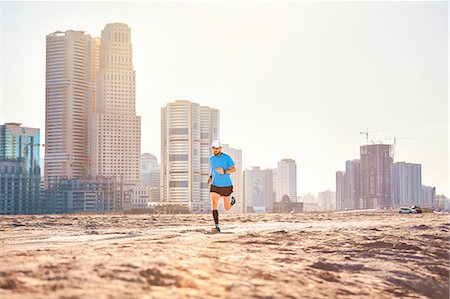 simsearch:614-08535671,k - Mid adult man running on sand by skyscrapers, Dubai, United Arab Emirates Photographie de stock - Premium Libres de Droits, Code: 614-08487799