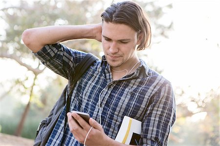 Angled view of young man, hand to head, looking down at smartphone Photographie de stock - Premium Libres de Droits, Code: 614-08487867