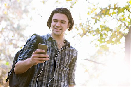 simsearch:614-07652557,k - Low angle view of young man holding smartphone looking down smiling Stock Photo - Premium Royalty-Free, Code: 614-08487868