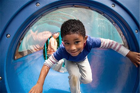 emerging - Boy bending forward emerging from playground tunnel Stock Photo - Premium Royalty-Free, Code: 614-08487892