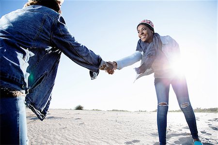 simsearch:614-08578277,k - Two friends fooling around at beach, holding hands, smiling Foto de stock - Sin royalties Premium, Código: 614-08487941