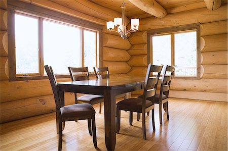 Wooden dining table and high-back chairs in dining room of a Scandinavian cottage style log home Fotografie stock - Premium Royalty-Free, Codice: 614-08488006