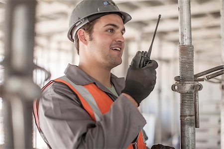 Builder using walkie talkie on construction site Stock Photo - Premium Royalty-Free, Code: 614-08488055