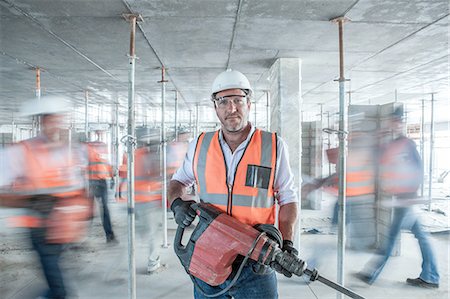simsearch:614-00383197,k - Mid adult male builder holding building equipment  on busy construction site Stock Photo - Premium Royalty-Free, Code: 614-08488090