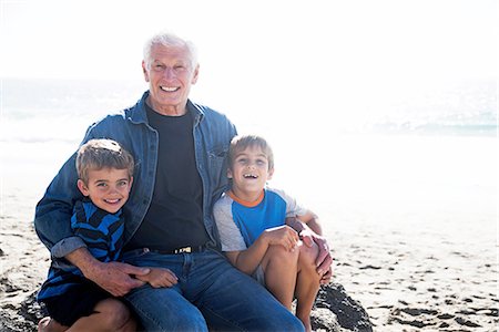 simsearch:614-07235015,k - Grandfather with two grandsons, sitting on beach, smiling Fotografie stock - Premium Royalty-Free, Codice: 614-08535646