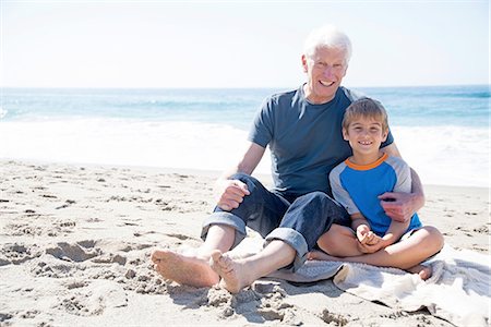 simsearch:614-07235020,k - Portrait of grandfather and grandson, sitting on beach, smiling Fotografie stock - Premium Royalty-Free, Codice: 614-08535642