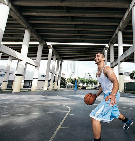 simsearch:614-08535667,k - Young man on basketball court holding basketball looking up smiling Stock Photo - Premium Royalty-Free, Code: 614-08535671