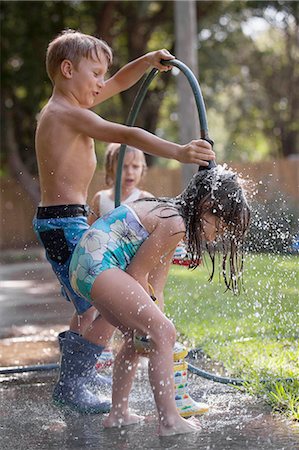 Children playing with water hose on sidewalk Stock Photo - Premium Royalty-Free, Code: 614-08535754