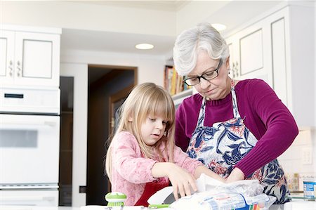 senior lifestyle cooking - Girl and grandmother preparing greaseproof paper Stock Photo - Premium Royalty-Free, Code: 614-08535817