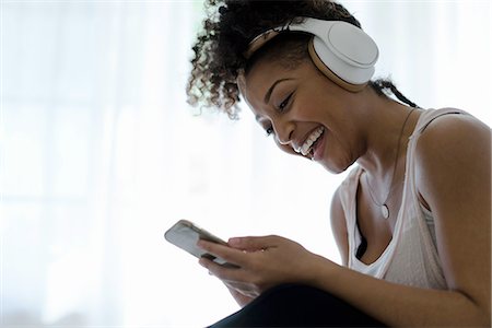 skype - Woman wearing headphones, looking at smartphone, laughing Foto de stock - Sin royalties Premium, Código: 614-08535846