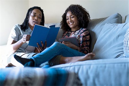 Lesbian couple relaxing sofa, reading book and using digital tablet Foto de stock - Sin royalties Premium, Código: 614-08535849