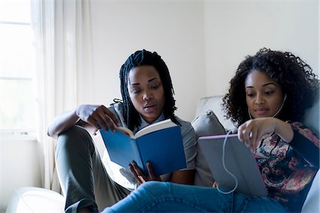 Lesbian couple relaxing sofa, reading book and using digital tablet Stock Photo - Premium Royalty-Free, Code: 614-08535850