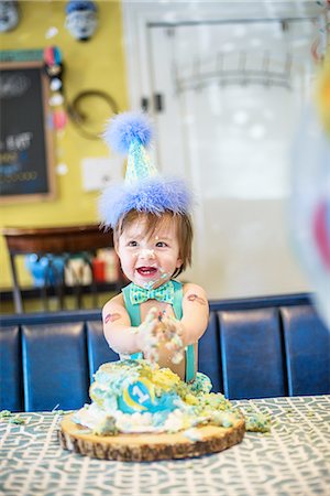 Baby boy wearing party hat smashing first birthday cake at table Stock Photo - Premium Royalty-Free, Code: 614-08535898