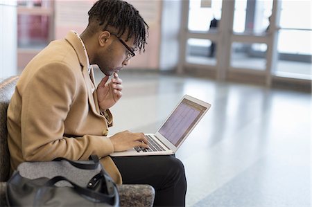 simsearch:614-08578376,k - Young businessman sitting in train station typing on laptop Fotografie stock - Premium Royalty-Free, Codice: 614-08535914