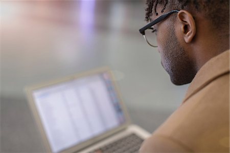 simsearch:614-08578376,k - Over shoulder view of young businessman sitting in train station using laptop Fotografie stock - Premium Royalty-Free, Codice: 614-08535915