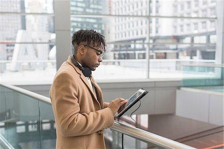 enroute - Young businessman using touchscreen on digital tablet in train station atrium Stock Photo - Premium Royalty-Free, Code: 614-08535918