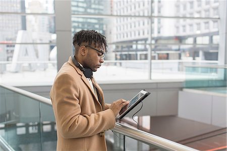 simsearch:614-08329517,k - Young businessman using touchscreen on digital tablet in train station atrium Foto de stock - Royalty Free Premium, Número: 614-08535918