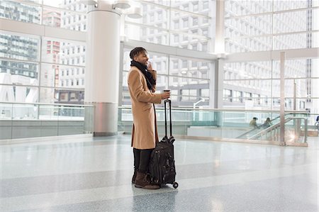 simsearch:614-08877313,k - Young businessman with wheeled case talking on smartphone in train station atrium Stock Photo - Premium Royalty-Free, Code: 614-08535923