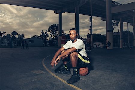 Man on basketball court sitting on basketball looking at camera Foto de stock - Sin royalties Premium, Código: 614-08544693