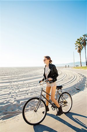 Young woman on bicycle gazing from beach, Venice Beach, California, USA Stock Photo - Premium Royalty-Free, Code: 614-08544735