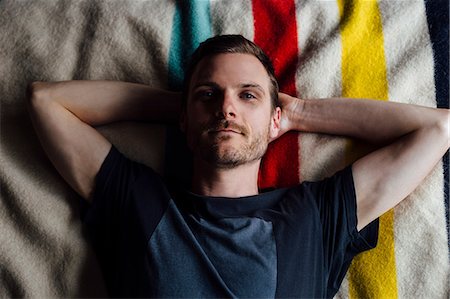 simsearch:693-03312486,k - Overhead portrait of confident man lying on striped blanket with hands behind head Photographie de stock - Premium Libres de Droits, Code: 614-08544957