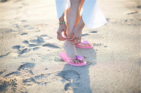 pink flip flops beach - Cropped shot of woman fastening anklet on Santa Monica beach, Cresent City, California, USA Stock Photo - Premium Royalty-Free, Code: 614-08544997