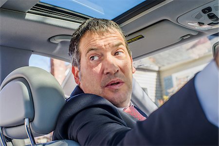 reversing - Business man in car looking over shoulder Stock Photo - Premium Royalty-Free, Code: 614-08545042