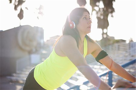 Woman wearing headphones and activity tracker doing standing push ups looking away Stock Photo - Premium Royalty-Free, Code: 614-08578291