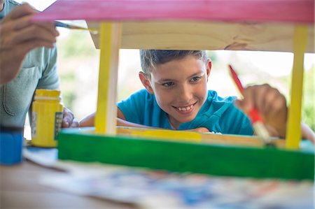 simsearch:6111-06838117,k - Father and son doing crafts together, painting wooden birdhouse Stock Photo - Premium Royalty-Free, Code: 614-08578459