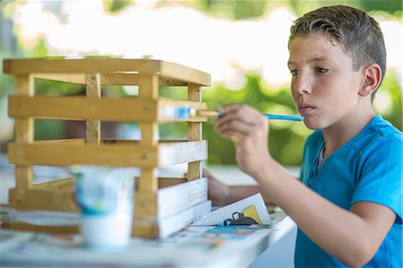 Young boy painting wooden crate Stock Photo - Premium Royalty-Free, Code: 614-08578464