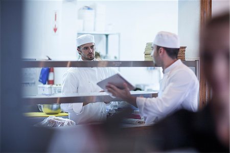 Chefs discussing orders in kitchen Foto de stock - Sin royalties Premium, Código: 614-08578578