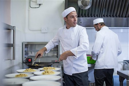 Chef filling plates with pasta in kitchen Photographie de stock - Premium Libres de Droits, Code: 614-08578573