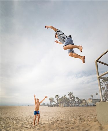 Young man jumping toward boy's open arms on Venice Beach, California, USA Stock Photo - Premium Royalty-Free, Code: 614-08578708