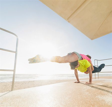 simsearch:614-08270510,k - Couple practising partner yoga on beach lifeguard tower Photographie de stock - Premium Libres de Droits, Code: 614-08578701