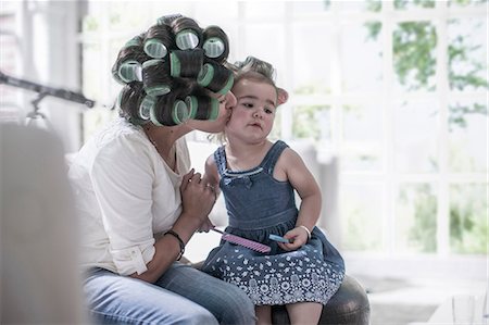 Mother in hair rollers kissing daughter's cheek Stock Photo - Premium Royalty-Free, Code: 614-08641539