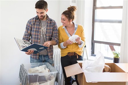 photoalbums inside - Moving house: Young couple unpacking boxes, looking through photo album Stock Photo - Premium Royalty-Free, Code: 614-08641557