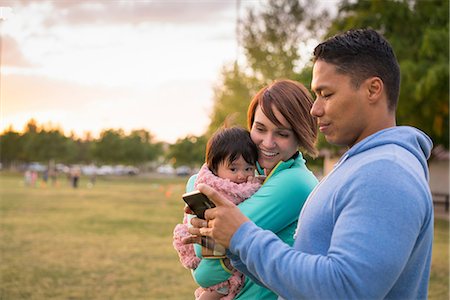 father and baby girl in park - Couple with baby, using mobile phone in park Stock Photo - Premium Royalty-Free, Code: 614-08641637