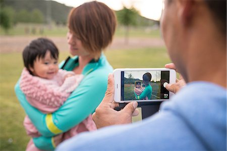 Father taking photograph of mother and baby in park Stock Photo - Premium Royalty-Free, Code: 614-08641632