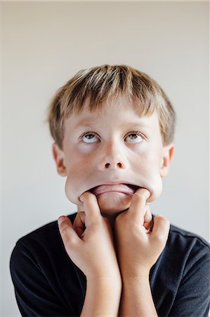 pull funny - Studio portrait of boy pulling face with fingers in mouth Stock Photo - Premium Royalty-Free, Code: 614-08641685