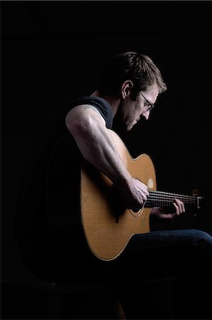 Low key shot of mid adult man playing acoustic guitar Stock Photo - Premium Royalty-Free, Code: 614-08641712