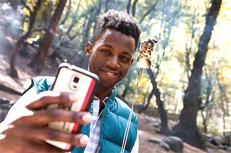 simsearch:614-08720980,k - Young male hiker taking smartphone selfie with toasted marshmallow in forest, Arcadia, California, USA Stock Photo - Premium Royalty-Free, Code: 614-08641890
