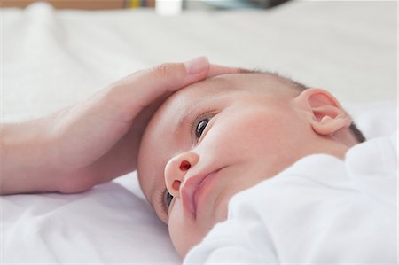 Mothers hand stroking baby boys head Stock Photo - Premium Royalty-Free, Code: 614-08684705