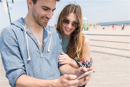 Couple looking at smartphone smiling, Coney island, Brooklyn, New York, USA Foto de stock - Sin royalties Premium, Código: 614-08684878