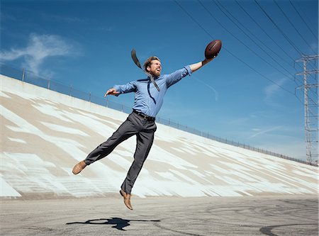 Businessman catching american football on Los Angeles river, California, USA Stock Photo - Premium Royalty-Free, Code: 614-08684901